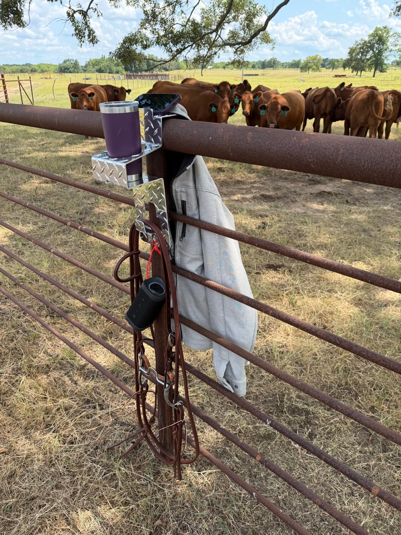 image of pipe rail fence with DrinkinBuddy utility drink holder hanging on pipe rail fence